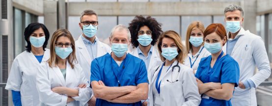 A group of doctors with face masks looking at camera, corona virus concept.